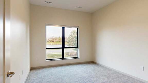 a bedroom with a large window and carpeted flooring