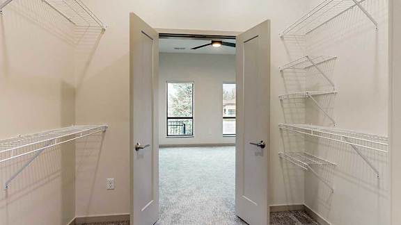 a walk-through closet with double doors opening into the bedroom