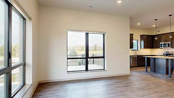 a spacious living room with hardwood floors and a window looking out onto the walk-out patio