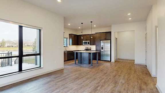 an open kitchen and living room with hardwood floors and a large window