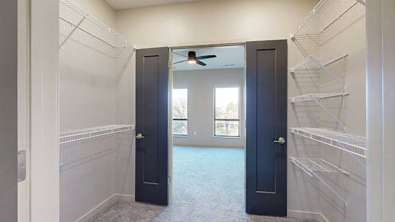 a walk-through closet with dark grey double doors and built-in wire shelving
