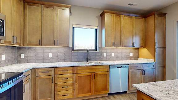 a kitchen with light brown wooden cabinets and a sink with a window above it