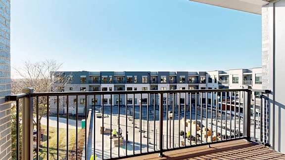 A balcony with a metal railing, overlooking a courtyard.