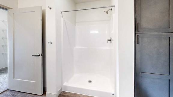 A bathroom with a walk-in shower with brushed nickel fixtures.