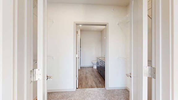 A walk-through closet with wire shelving on either side, and a door open to an attached bathroom.