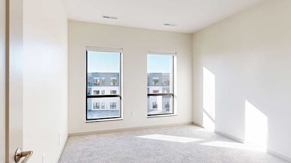 A carpeted bedroom with floor-to-ceiling windows.