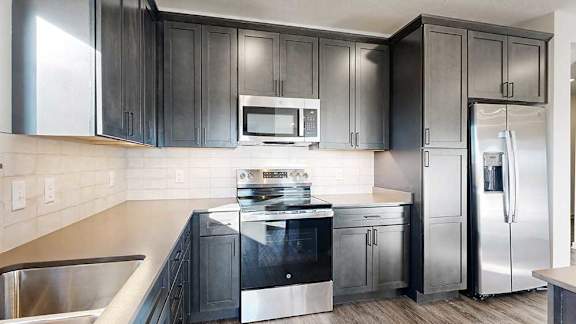 A close up of the stainless steel microwave and range in a kitchen with dark wooden cabinets.