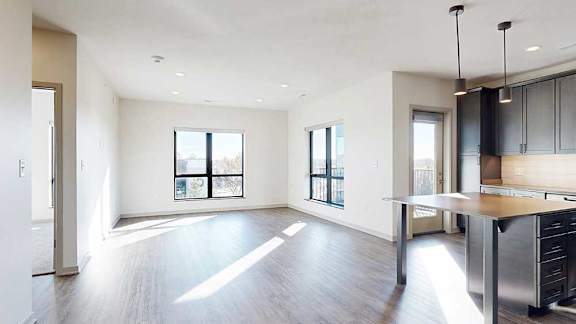 A living room with hardwood-style flooring and floor-to-ceiling windows.