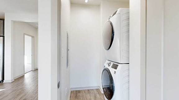A stacked full-sized washer and dryer in a laundry room.