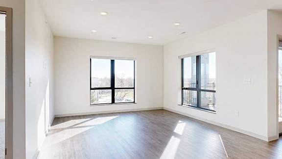 A living room with hardwood-style flooring and floor-to-ceiling windows.
