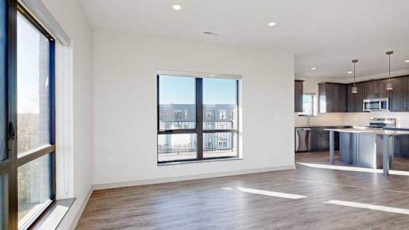 A living room with hardwood-style flooring and floor-to-ceiling windows.