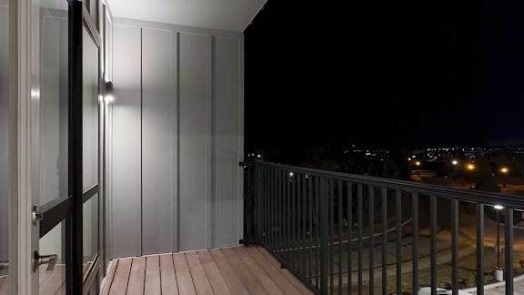 a balcony with a metal railing and a window into the bedroom