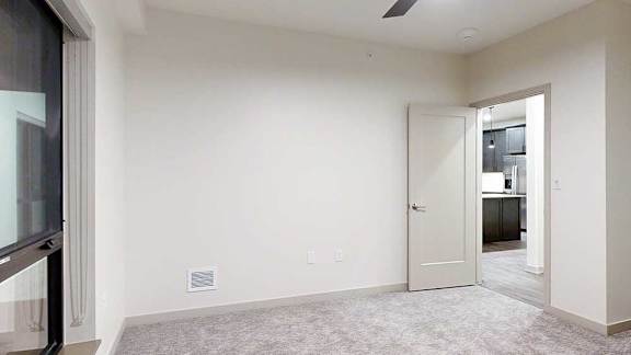 a bedroom with carpeted flooring, white walls, and a large window