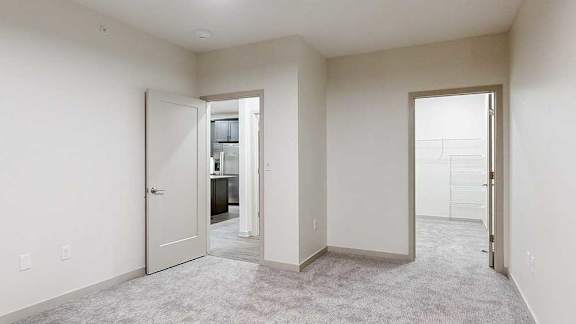 a bedroom with carpeted flooring and a walk-in closet