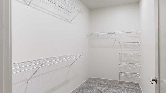 a white walk in closet with built in shelves and hanging space