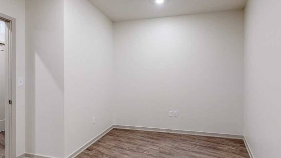 a den with white walls and hardwood flooring
