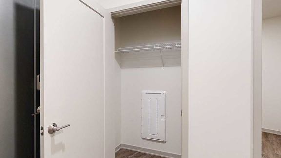 a coat closet in the hallway with a built in shelf