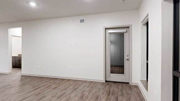 a living room with hardwood flooring and a windowed door to a balcony