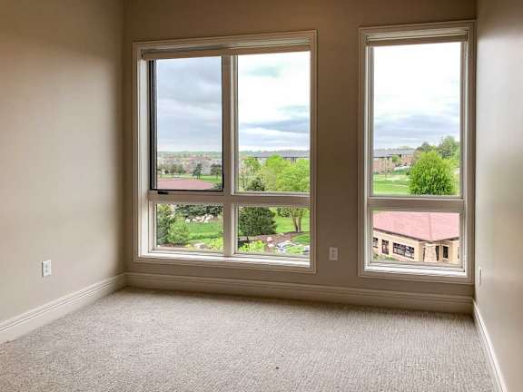 a bedroom with floor-to-ceiling windows overlooking a residential area