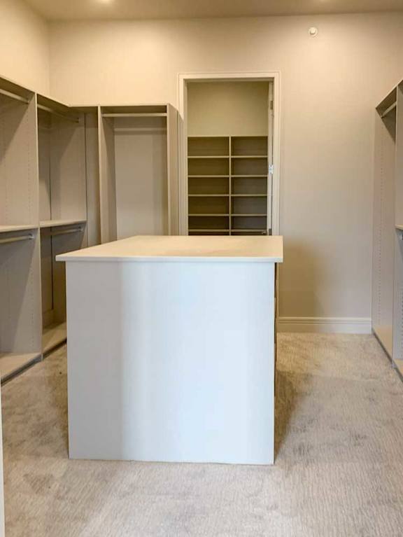 a spacious walk-in closet with built-in shelving and hanging space, and a central storage island