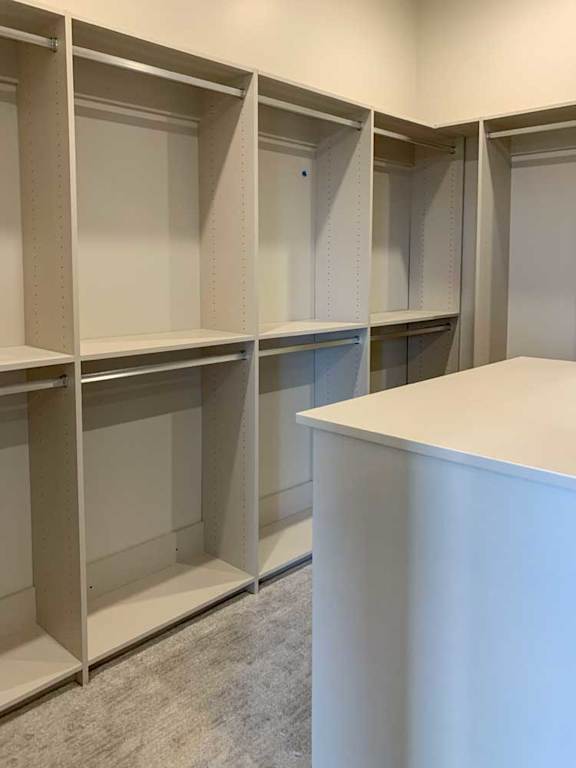 a spacious walk-in closet with built-in hanging spaces and a central cabinet