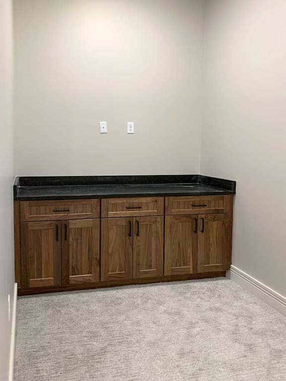 a carpeted den space with a built-in cabinet with marble countertop