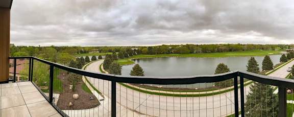 a balcony the neighboring golf course pond and a green landscape