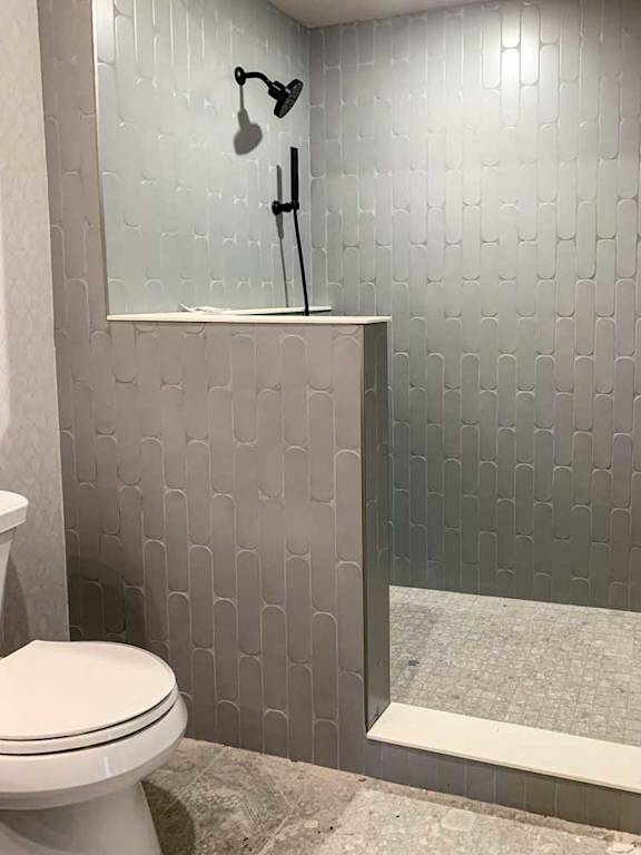 a bathroom with a large tiled walk-in shower with a built-in divider wall