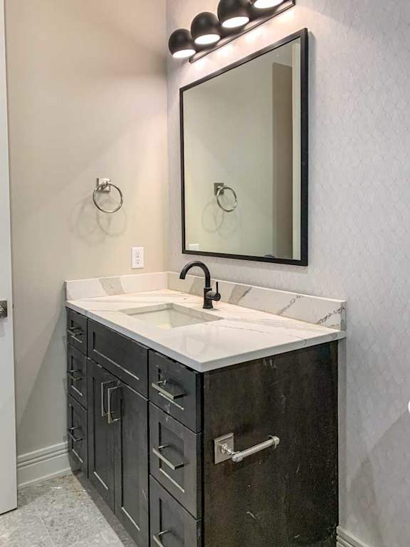 a hallway bathroom with a dark wooden sink and white marble countertop with a wide mirror