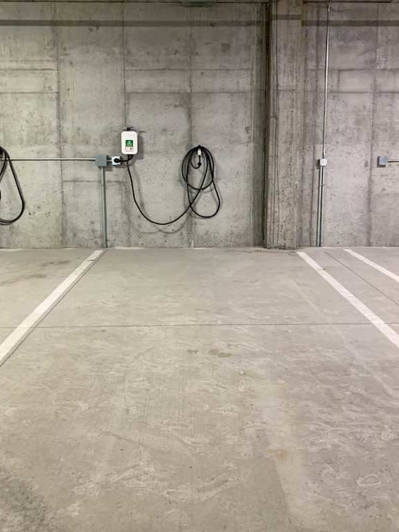 a parking space with a wall-mounted EV charger in the underground climate-controllled garage