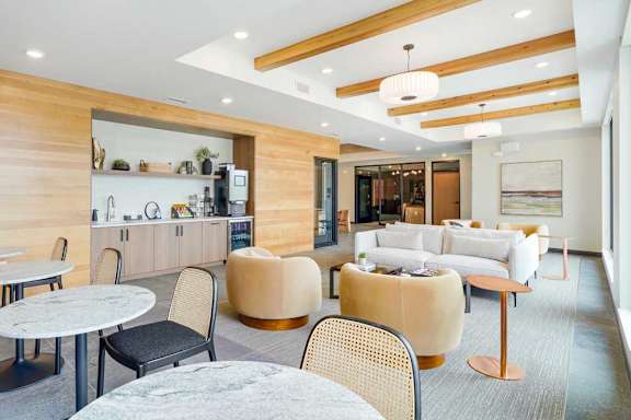 a modern, cafe-style lounge with armchairs, couches, tables and chair, and a coffee bar