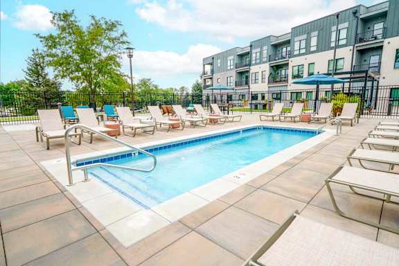 A lounge pool surrounded by several lounge chairs and umbrellas for shade.