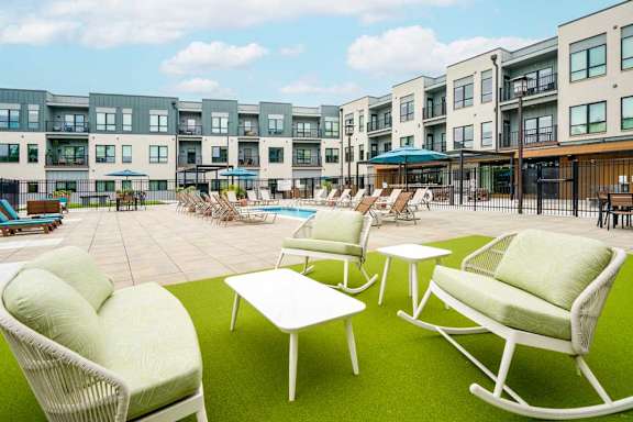 A patio space in the courtyard, with bench seating and rocking chairs on turf.