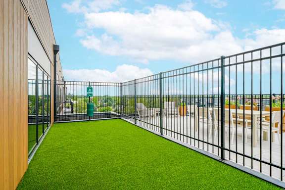 a fenced-in turf dog run with a waste station on the penthouse rooftop patio
