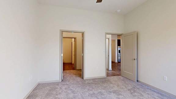 A room with carpeted floor and three doors.