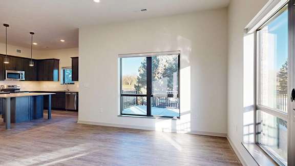A modern kitchen with dark wood cabinets and a large window overlooking a patio.
