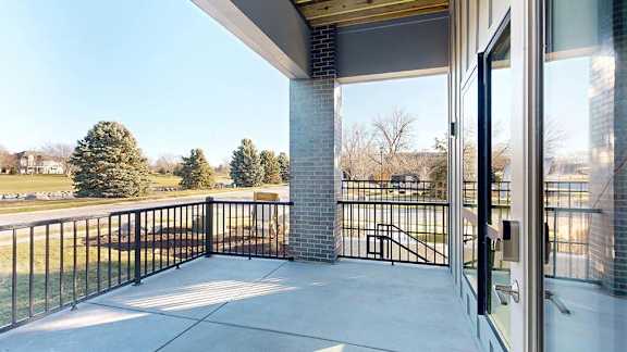 Covered apartment patio with a private entrance, metal railing, and open neighborhood views.