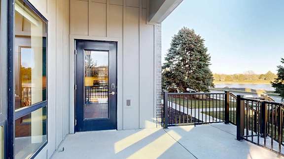 Covered apartment patio with a private entrance and metal railing.