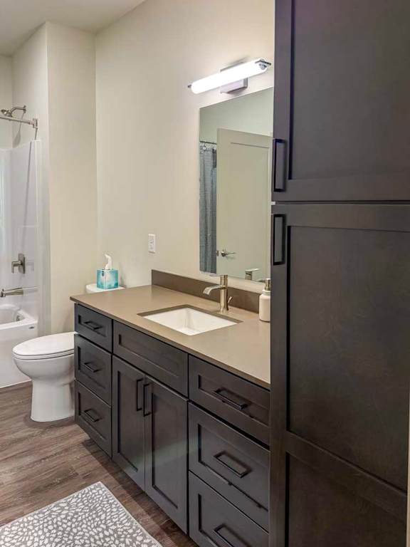 Bathroom with single vanity, dark cabinets, and tub-shower combo.