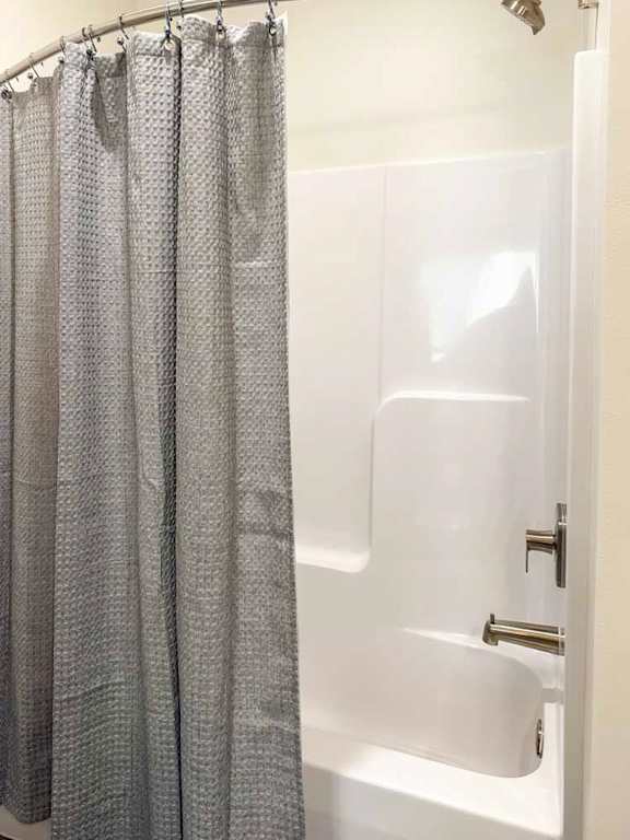 Bathroom with tub and shower combo and curtain.