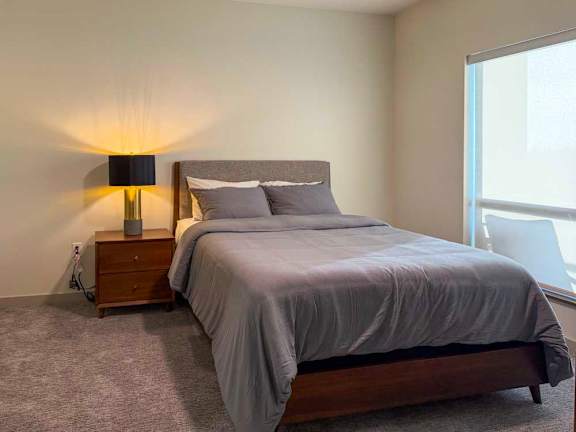 A bedroom with a large bed and a lamp on the side table.