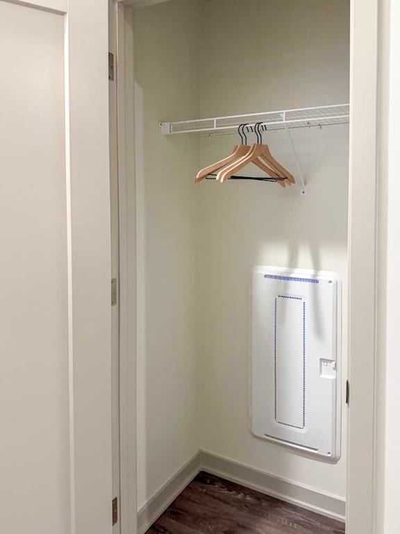 Small coat closet with shelf, hangers, and panel access.