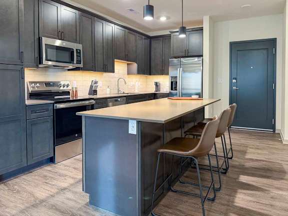 Kitchen with large island, bar seating, and stainless steel refrigerator.