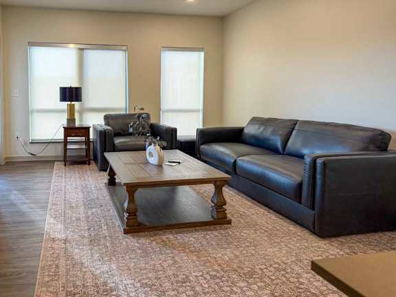 A living room with a black leather couch and a wooden coffee table.