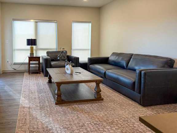 Living room with sofa, armchair, coffee table, and large windows.