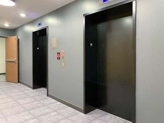two elevators with black doors in a tiled room