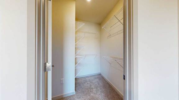 An L-shaped walk-in closet with several built-in shelves.