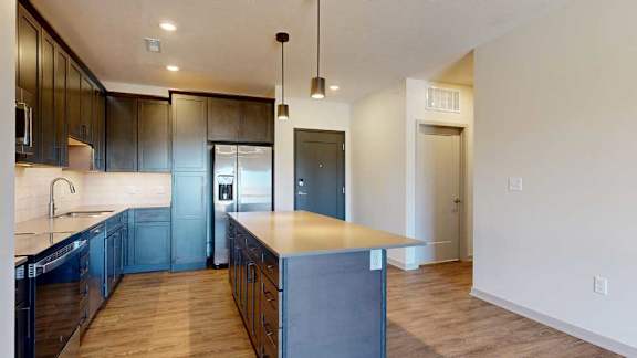 A front entryway next to a modern kitchen with dark cabinets and stainless steel appliances.