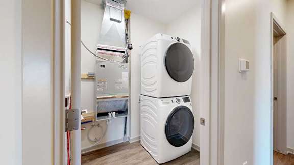 A stacked full-sized washer and dryer in a laundry room.