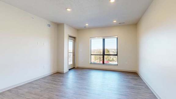 A living room with hardwood-style flooring and floor-to-ceiling windows.